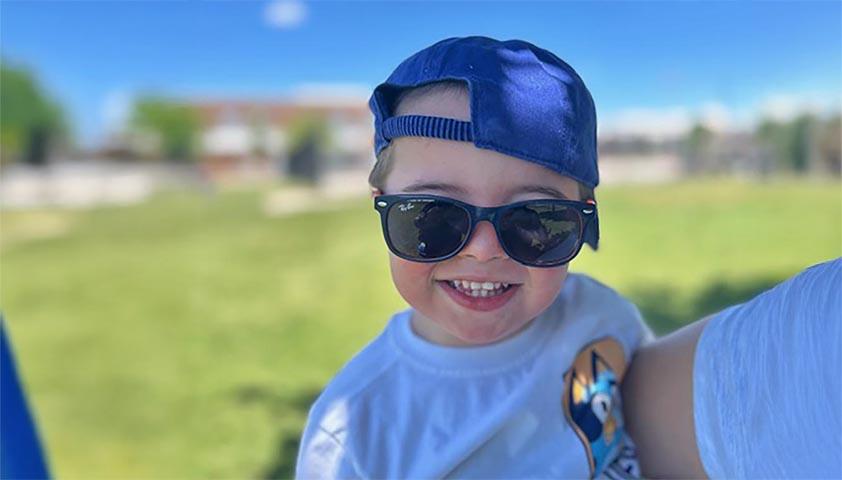 A boy with sunglasses on and a big smile
