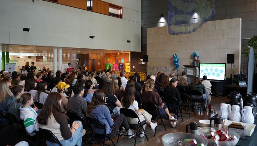 people sitting in an atrium attending an award ceremony