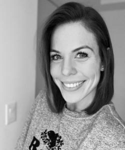 Woman with dark shoulder-length hair wearing a gray Roots sweater