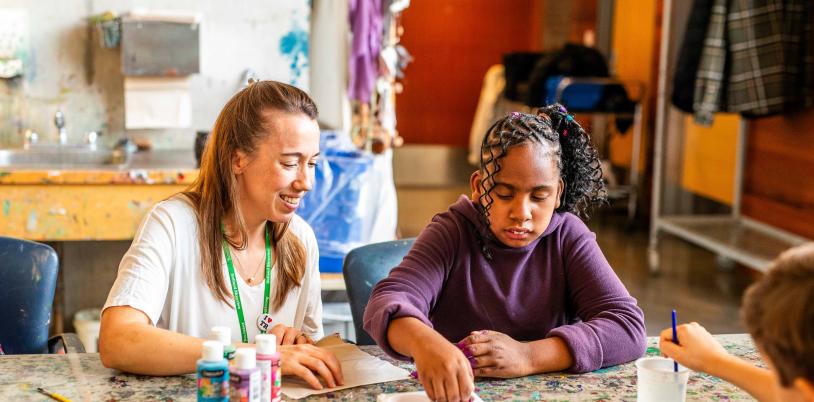 Tayah and a staff member seated at a table, painting