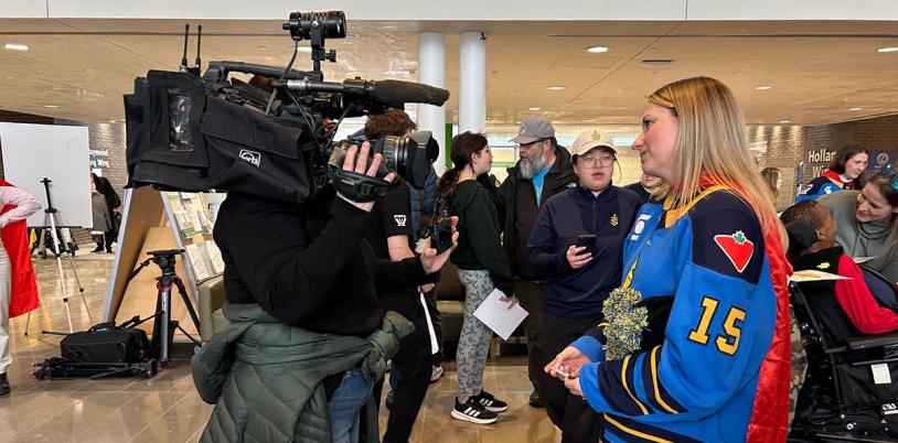 An adult is being interviewed by a camera reporter