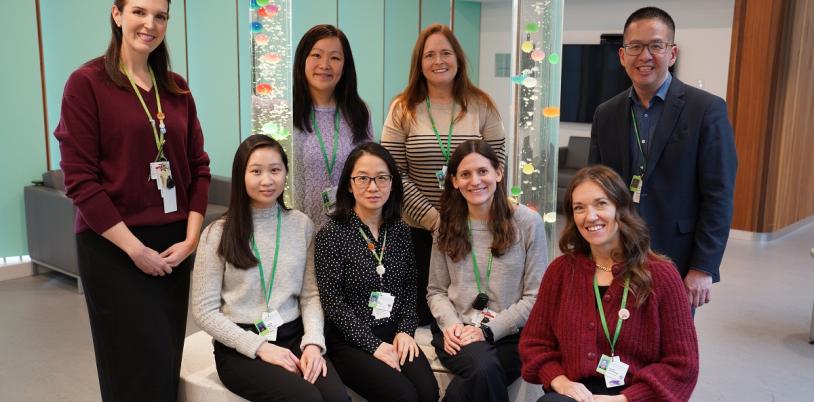 group of adults, some sitting and others standing, in a room with bubble towers in the background