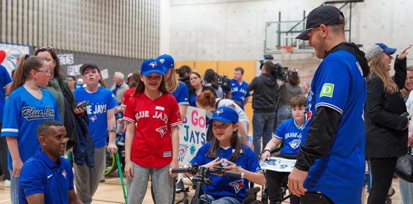 A kid on wheelchair accompany with some adults in a basketball courtyard