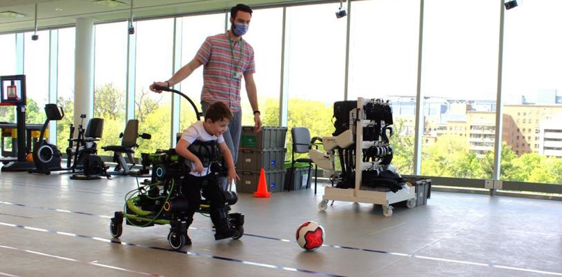 A child using the Trexo to kick a soccer ball indoors