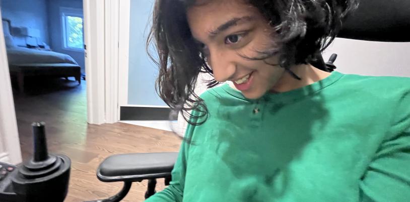 Teen with dark wavy hair and green shirt smiles