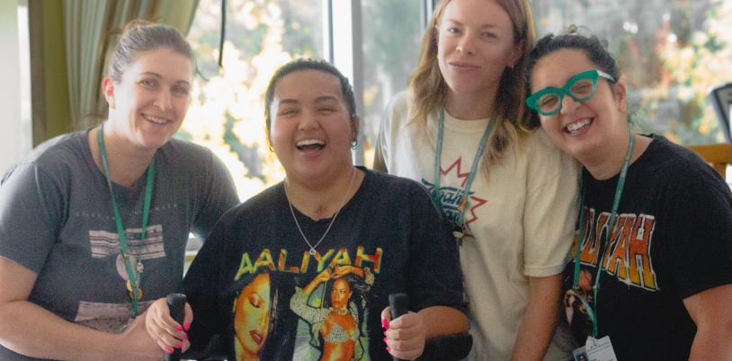 Teen wearing bright shirt and using walker surrounded by three women