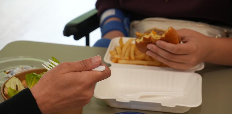 A parent and child eat salad, french fries and a burger.