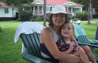 Woman with white sun hat in beach chair holding young boy