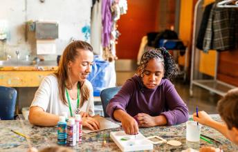 Tayah and a staff member seated at a table, painting