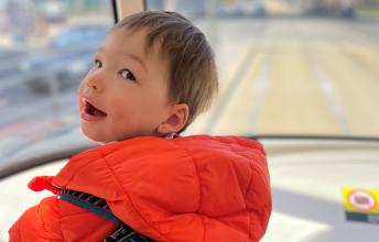 James standing at the front of a streetcar, behind the window, looking over his shoulder