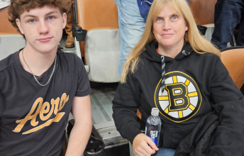A teenage boy and his mom sit together at a hockey game.