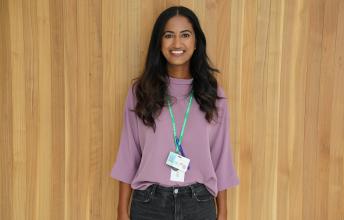 Woman with long dark hair and purple shirt wearing a green lanyard