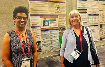 Dr. Selamesh Tsige-Legas and Dr. Darcy Fehlings stand in front of a research poster