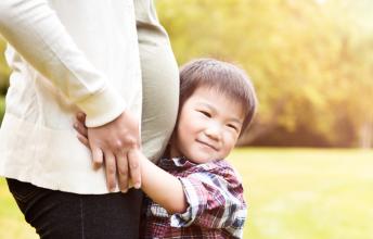 Boy hugs belly of pregnant woman