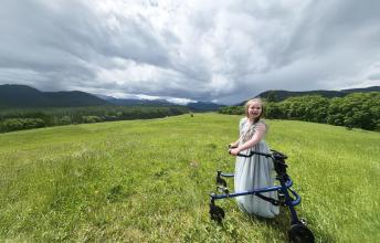 A child with walker is in the grass field