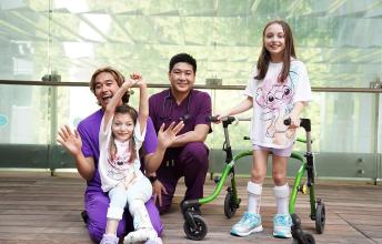 Two adults nurses are having group photos with two children patients