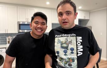 Two young men with kitchen behind them