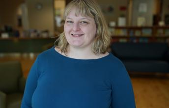 Woman with blonde hair and blue sweater in library