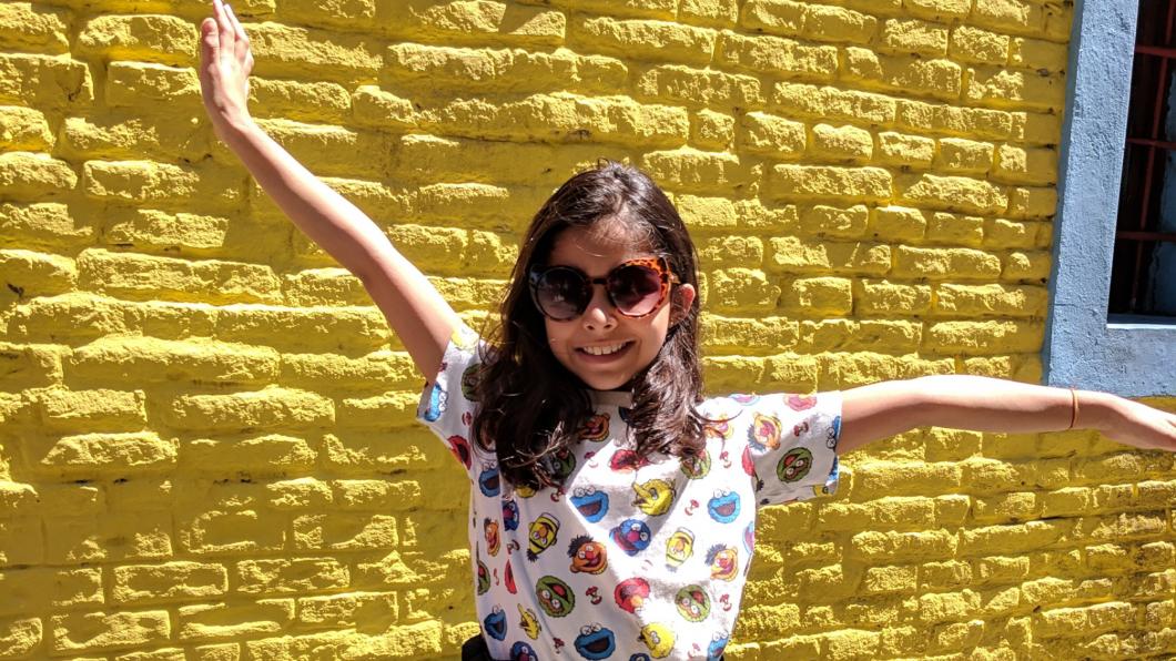 Rhea standing in front of a yellow brick wall