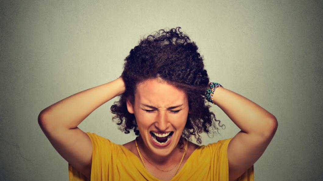 Woman holding head and screaming