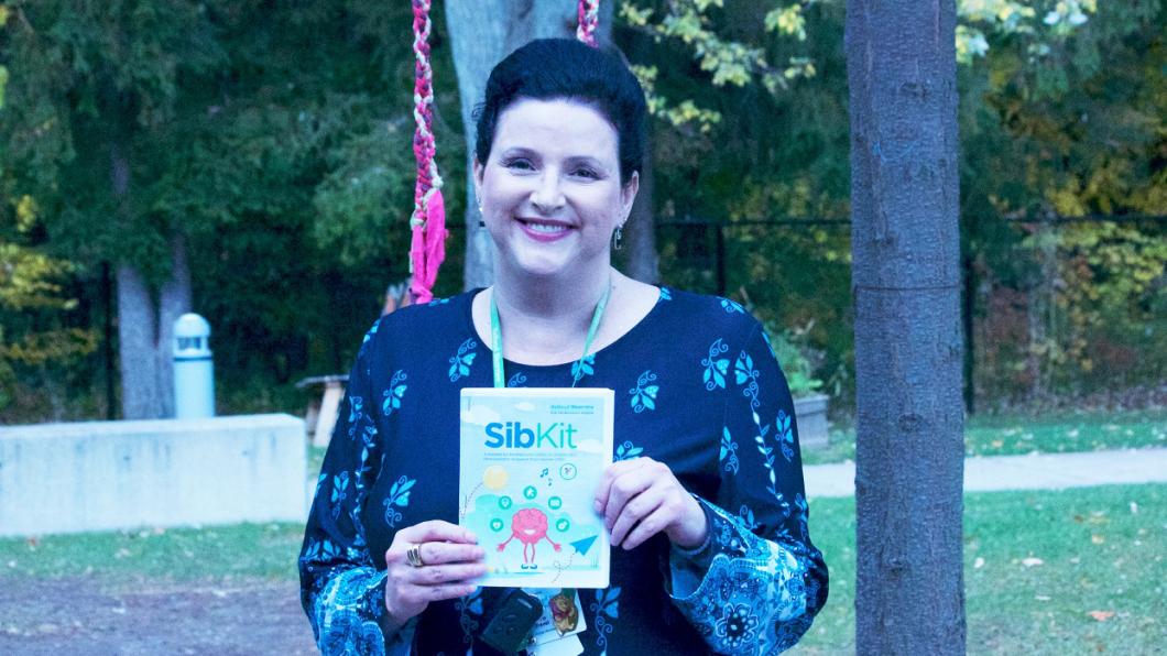 Woman holding book called SibKit