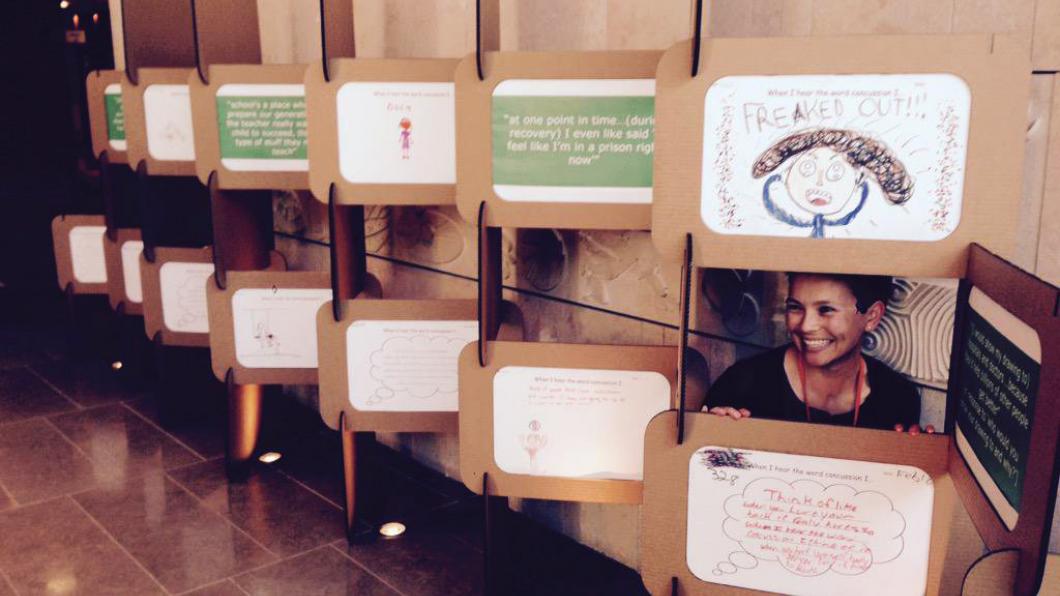 Woman crouches behind display of children's drawings