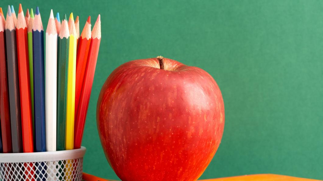 apple and colouring pencils on a desk