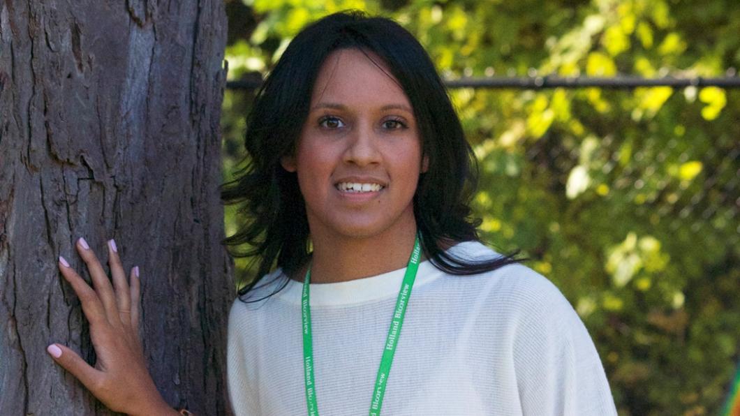 Young woman with hand on tree trunk