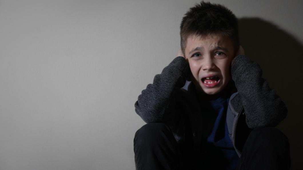 Distressed boy sits against wall