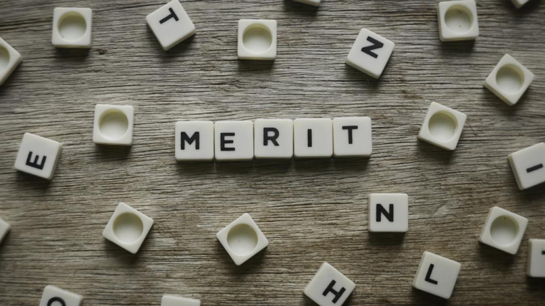 The word merit spelled with Scrabble pieces