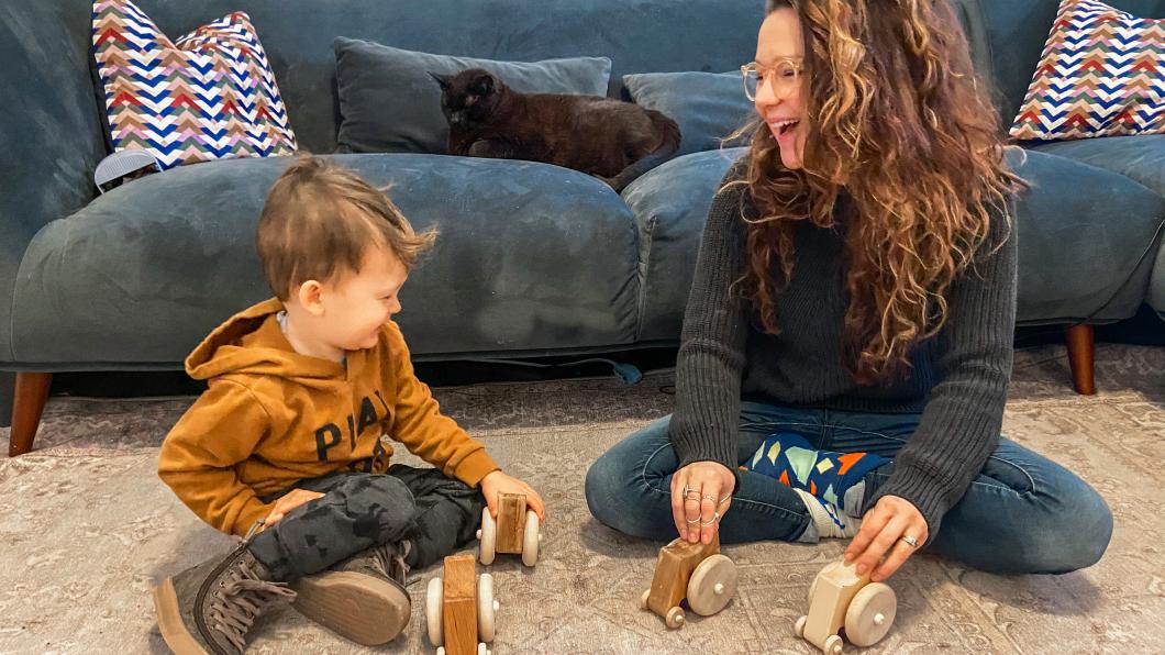 Mother and preschool son playing with wooden wheelchair toys