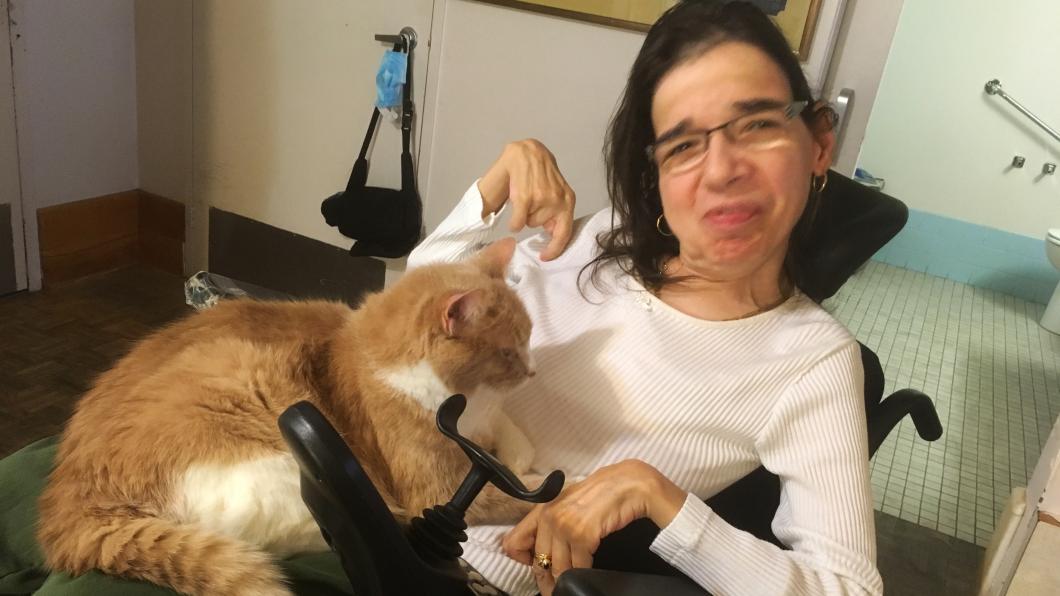 Woman in wheelchair with orange and white cat in her lap