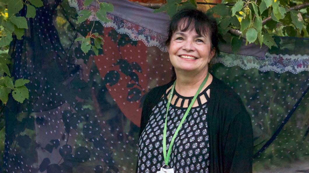 Woman with big smile standing in front of scarf drawn between two trees