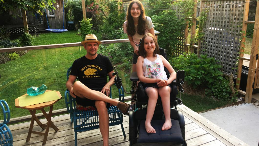 Father and two daughters, one in a wheelchair, on the back garden porch