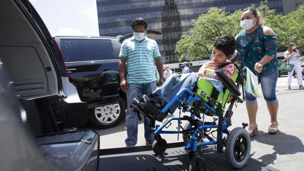 Mother pushing son in wheelchair into accessible van