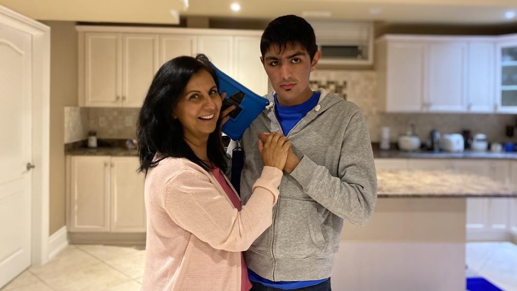 Mother with arms around young adult son in the kitchen