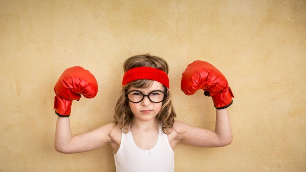 Young girl with glasses holding up red boxing gloves