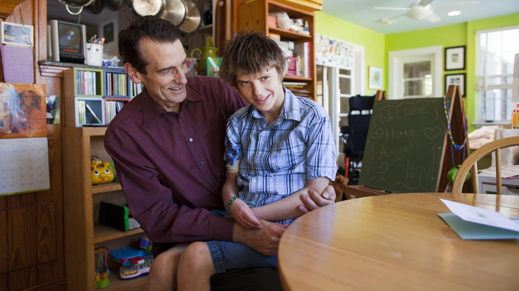 Man holding boy in his lap in the kitchen with both smiling