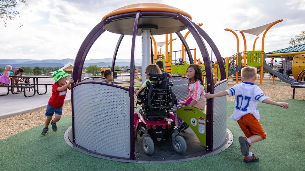 Spinning play equipment includes child in wheelchair and kids on seats