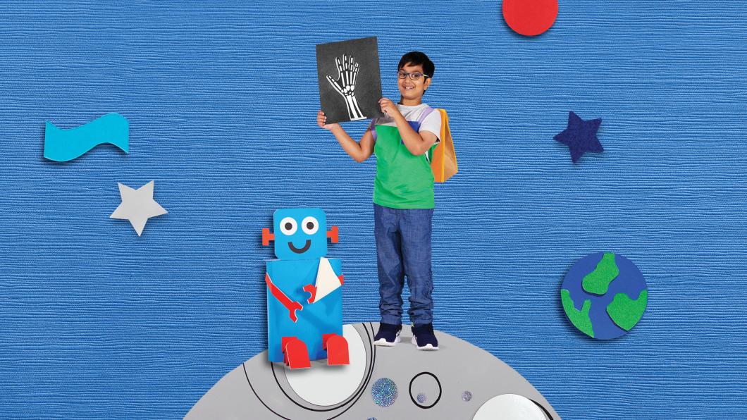 Brown-haired boy stands on a planet with a robot holding an X-ray and smiling