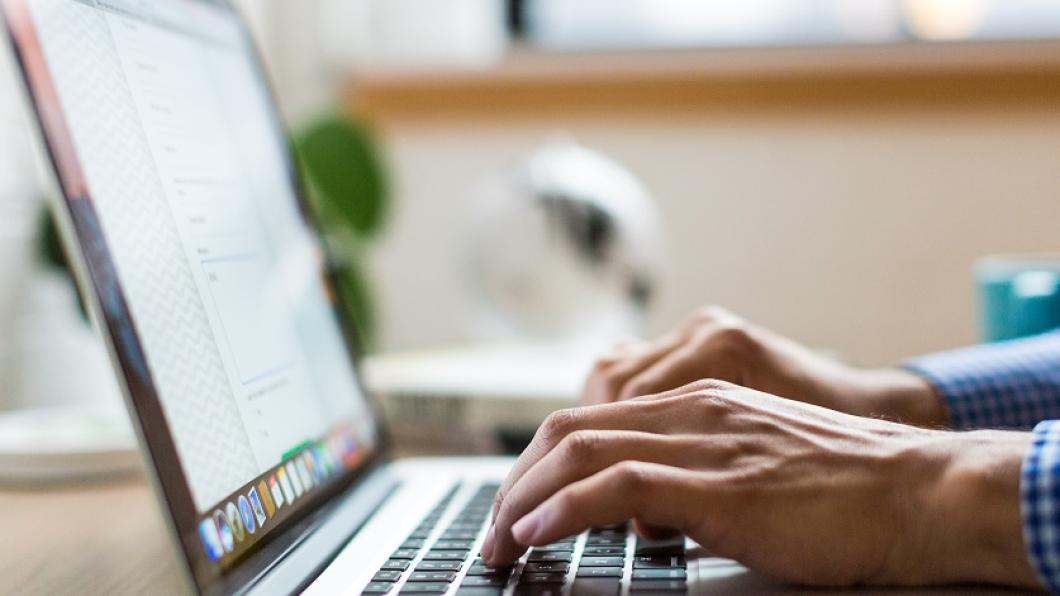 Adult typing on a keyboard by a window