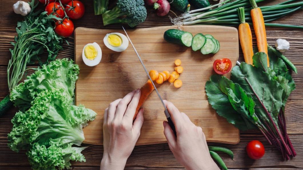 Hands preparing healthy vegetables and eggs on a cutting board