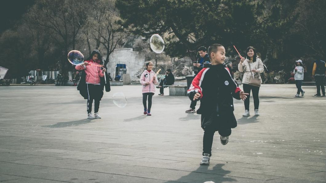 Boy and other children on playground with giant bubbles