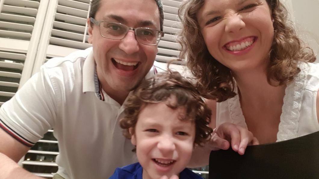 Woman with curly hair and big smile with man with glasses smiling and young boy with curly hair and smiles