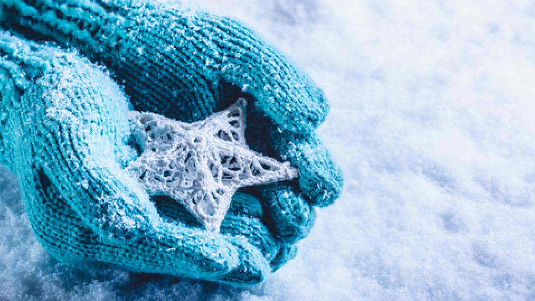 Light blue knitted gloves hold a detailed snowflake
