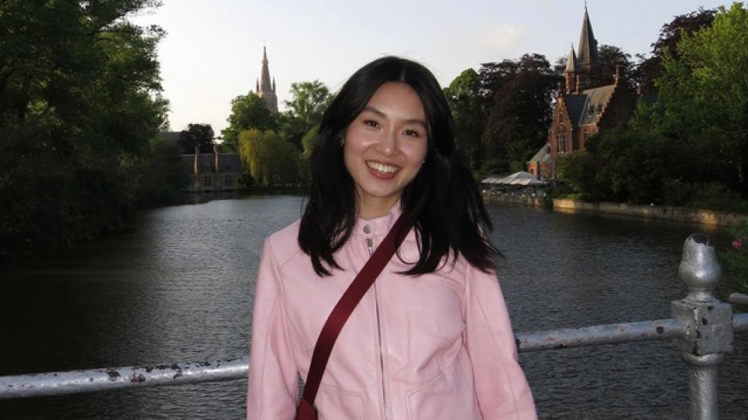 Woman in pink jacket on bridge with water and church steeples behind her