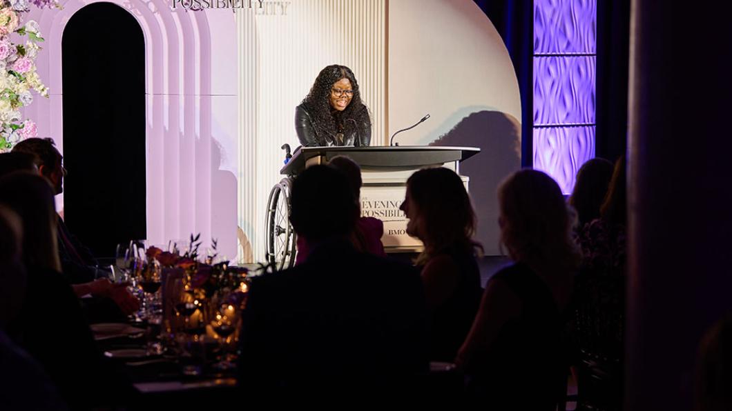 An adult giving speech to some audiences at a dark indoor setting