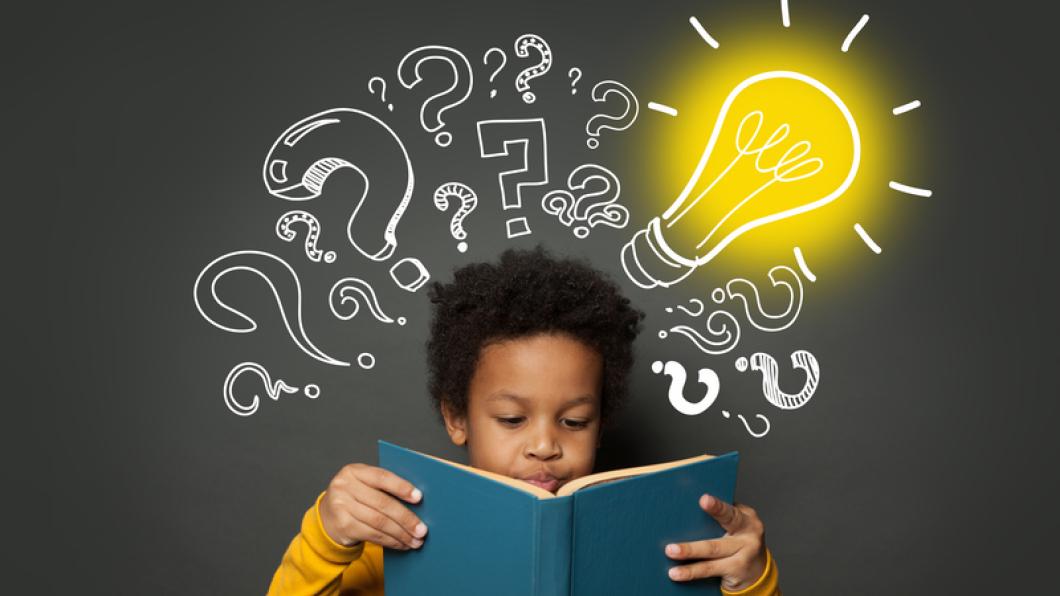 Image of boy with dark hair reading a blue book with lightbulbs and question marks in the background