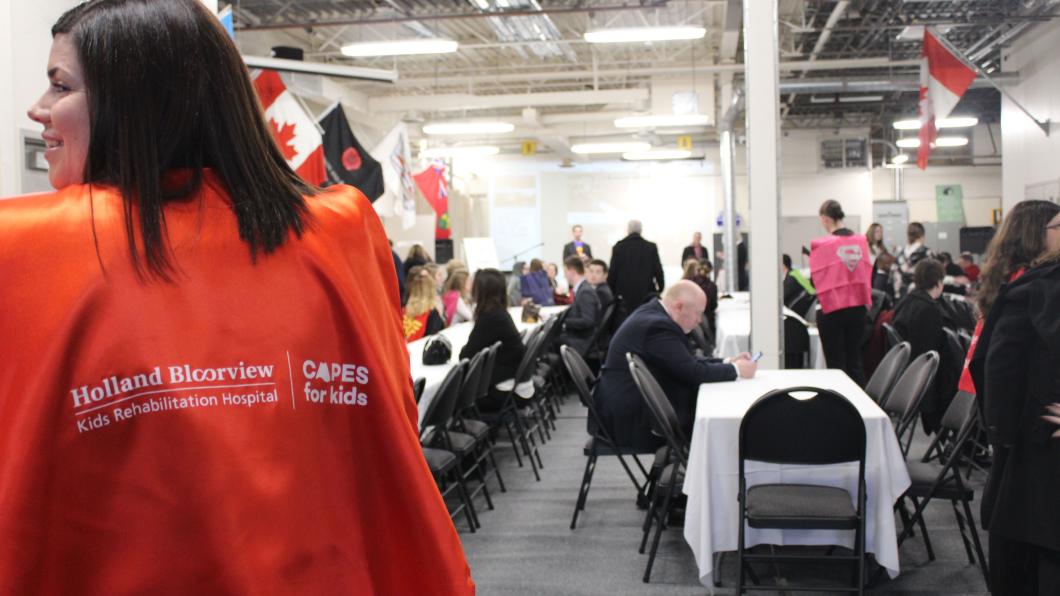 A person's turning back and their Capes for Kids Capes is shown, in an office setting.