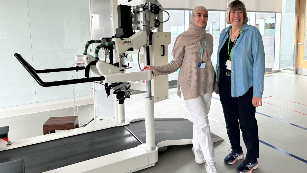 Two women stand in front of a robotic treadmill